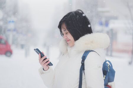Beautiful Asian girl using smartphone in winter day