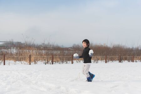 Cute Asian child playing on snow in the parkの写真素材