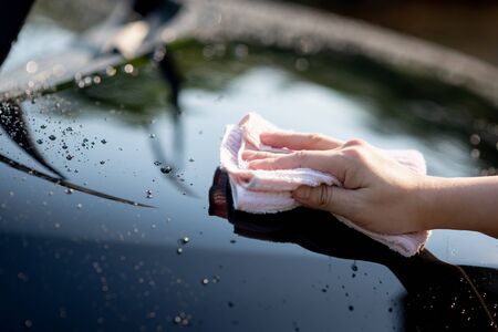 Close up of hand wiping water on black carの写真素材