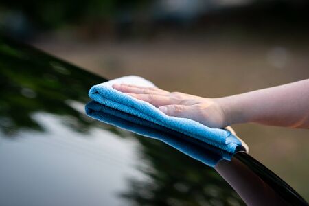 Close up of hand wiping water on black carの写真素材