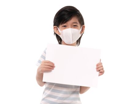 Cute Asian child with protection mask holding white paper on white background isolatedの写真素材
