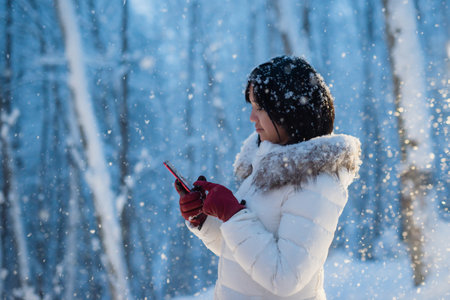Beautiful Asian short hair girl with a mobile phone in winter nightの写真素材