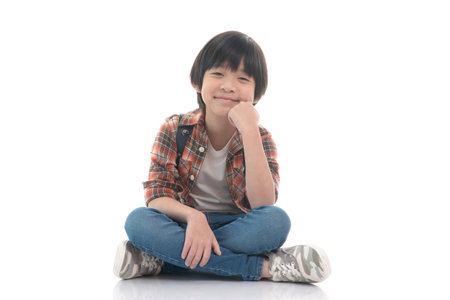Happy asian boy sitting on white background isolatedの写真素材