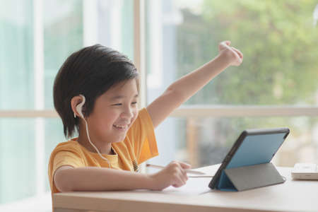 Cute Asian child learning class study online with video call from tablet at home .Social distancing ...