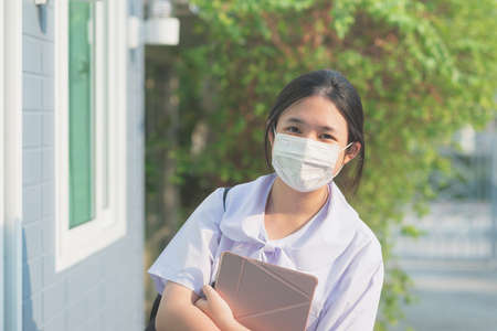 Asian student in uniform wearing medical mask going to schoolの写真素材