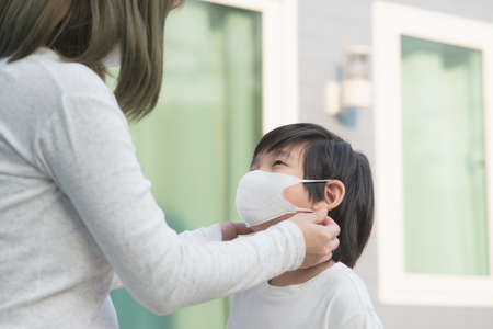 Asian mother puts a safety mask on her son's face.Back to school conceptの写真素材