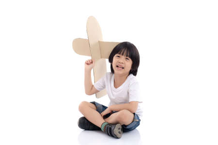 Cute Asian boy playing with cardboard airplane on white background isolatedの写真素材