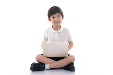 Cute Asian child sitting and using laptop on white background isolatedの写真素材