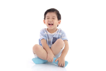 Happy asian boy sitting on white background isolatedの写真素材