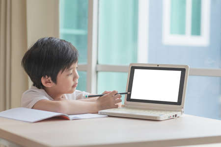 Cute Asian child learning class study online with a blank screen laptop at home .Social distancing  conceptの写真素材