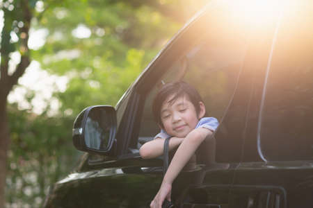 Asian child holding binoculars out of the car window on summer dayの写真素材