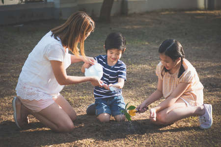 Cute Asian children and mother planting young tree on the black soil,Earth day conceptの写真素材