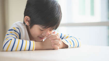 Cute Asian child boy praying with eyes closed in the morningの写真素材