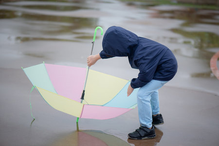 Happy asian boy holding colorful umbrella playing in the park after the rainの写真素材