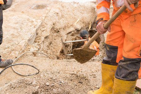 UPPER AUSTRIA: AUSTRIA April 11, 2017: Construction workers Construction workers are digging a trench for the Internet and power cables with excavator and shovel.のeditorial素材