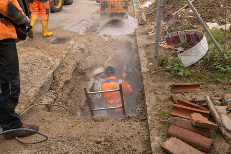 UPPER AUSTRIA: AUSTRIA April 11, 2017: Construction workers Construction workers are digging a trench for the Internet and power cables with excavator and shovel.のeditorial素材