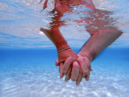 Underwater shot of a man and a woman's handsの写真素材