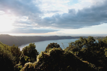 Light Filtering Under Dark Clouds on Lake Albano and the Surrounding Landscapeの写真素材