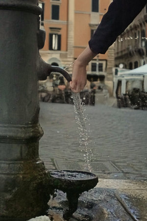 Pouring water from a fountain in Rome, Italy.の写真素材