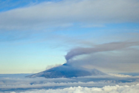 Aerial view of Mount Etna volcano erupting with plume of smoke and snow on the slopes above the...