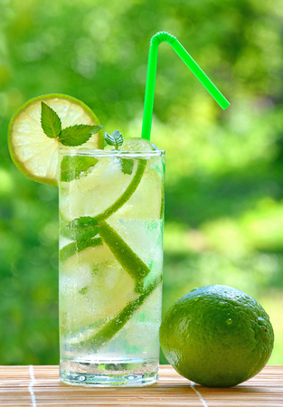 Cocktail mojito with lime and ice cubes on a blurred background.の写真素材