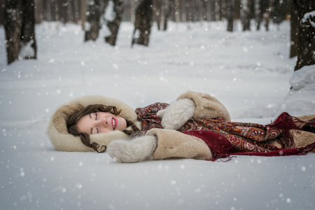 Happy girl lie around in soft snow on a winter day, rejoicing the snowfall.の写真素材