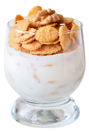 Yogurt with cornflakes and walnuts in a glass goblet isolated on a white background.の写真素材