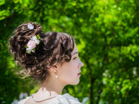 Portrait of a beautiful woman in a white dress with a hairstyle of bride in spring garden.の写真素材