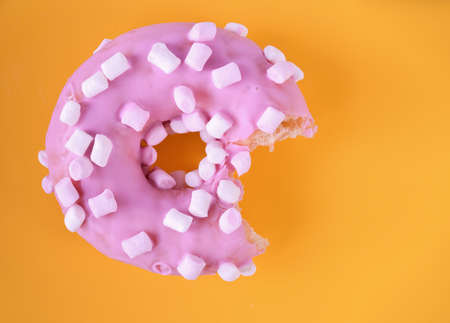 Strawberry donut covered with pink icing on green background.
