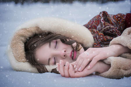 Woman lie around in soft snow on a winter day, rejoicing the snowfall.の写真素材