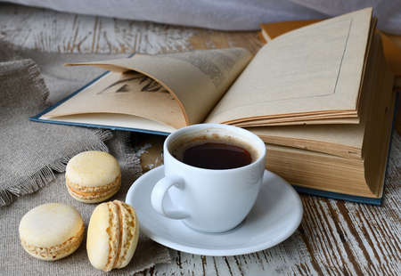 Still life with a cup of coffee, makroons and a book on the table.の写真素材