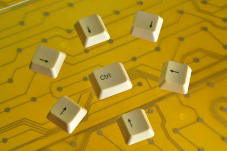Keyboard arrow keys surround the the key CTRL on yellow electric circuit in the backgroundの写真素材
