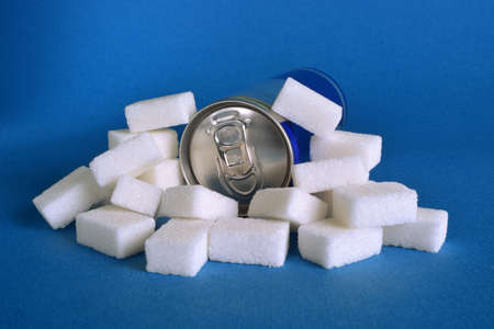 A can of sugary drink surrounded by white sugar cubes.
