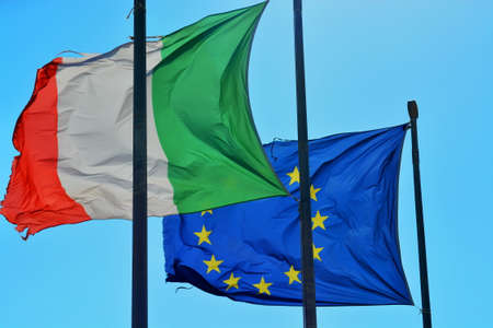 Worn waving flags of Italy and Europeの写真素材