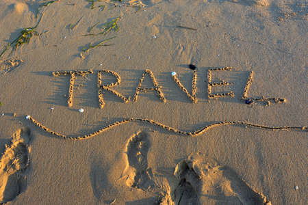 The word TRAVEL written on a sandy beach.の写真素材