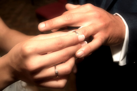 Bride's hand puts the wedding ring in the groom's fingerの写真素材