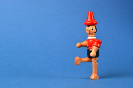 Wooden puppet depicting Pinocchio walking on a blue backgroundの写真素材