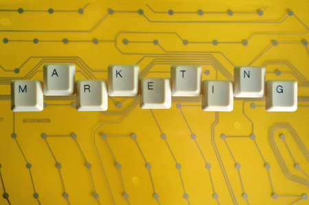 Keyboard keys form the word MARKETING on yellow electric circuit in the background.