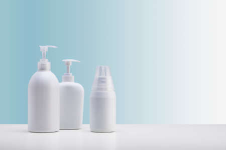 Set of three dispensers for cosmetics, on a white surface and a light blue background.の写真素材