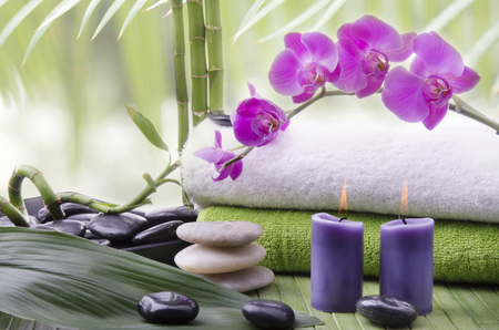 wellness environment with close-up of some bamboo stalks, aromatic candles, Stones for massage and beautiful purple orchid flowers.の写真素材