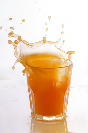 a fresh orange juice in the glass with splash on a white backgroundの写真素材