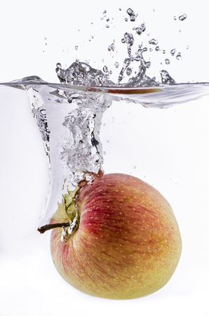 red and ripe apple falls into the water generating a big splashの写真素材