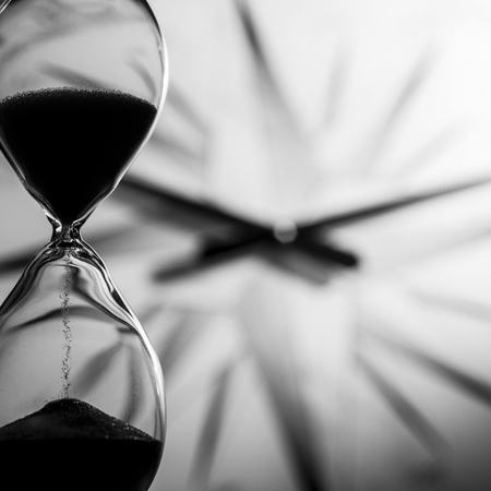 close-up of sand grains of an hourglass mark the expiration of time