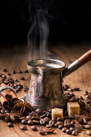 turkish coffee boiling in coffee pot and roasted coffee beans on wooden tableの写真素材
