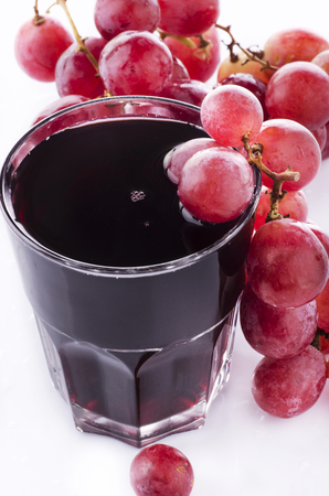 bunch of red grapes and fresh grape juice on a white backgroundの写真素材