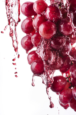bunch of red grapes and fresh grape juice on a white backgroundの写真素材
