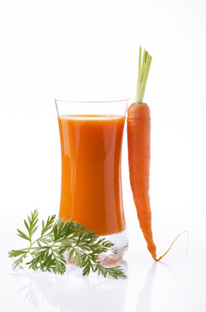 fresh carrot juice in glass beaker and whole carrots with white backgroundの写真素材