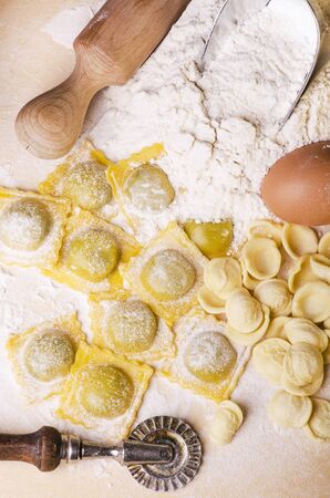 ravioli, homemade egg pasta, freshly prepared, Italian regional recipe on the table with rolling pin, sieve and ingredientsの写真素材