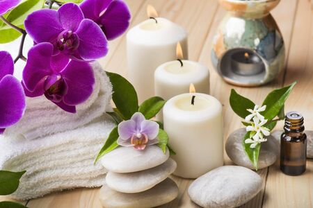 composition with orchid and jasmine flowers, some small bottles with essential oil, candles and light stones for massageの写真素材
