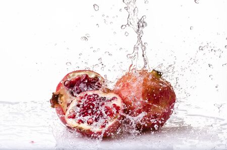 splash with fresh water on pomegranate isolated from the white backgroundの写真素材